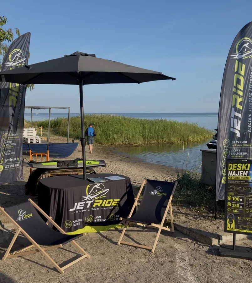 Stoisko JetRide na plaży nad Małym Morzem — parasol, leżaki i flagi reklamowe