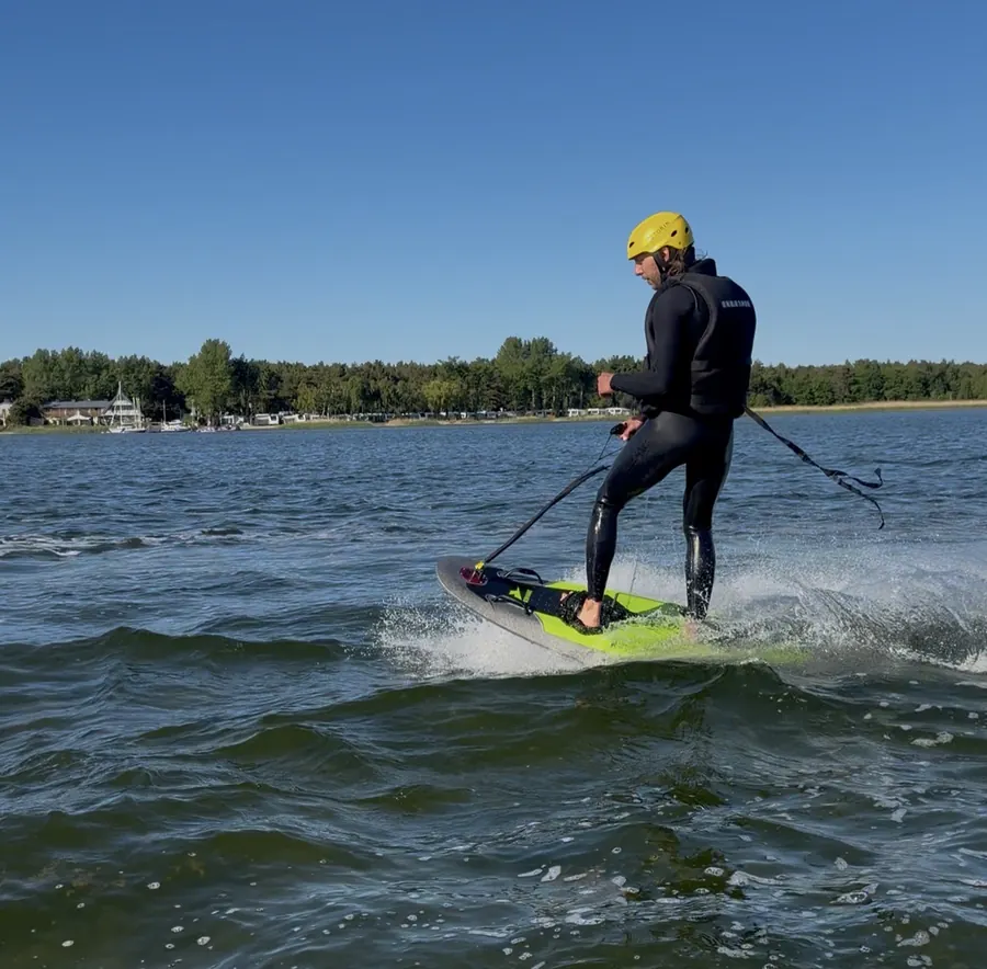 Jazda na elektrycznej desce surfingowej JetRide w kasku, tryskająca woda