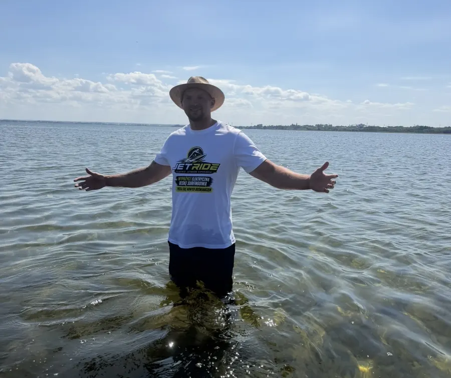 Klient JetRide stojący w wodzie Małego Morza w koszulce marki